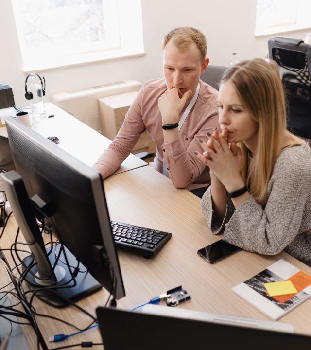Full concentration at work. Group of young business people working and communicating while sitting at the office desk together with colleagues sitting in the background